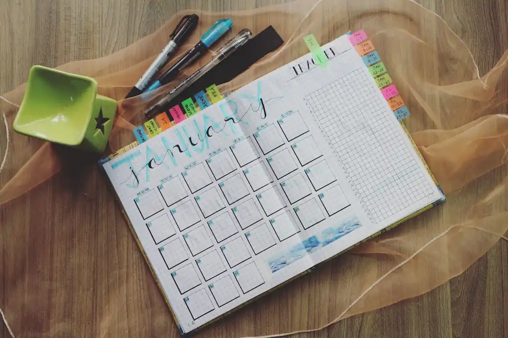 A calendar with pens on a table