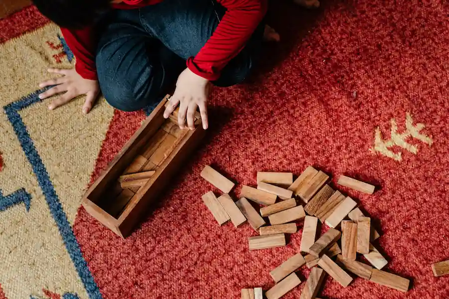 Jenga pieces scattered on a red carpet next to its container.
