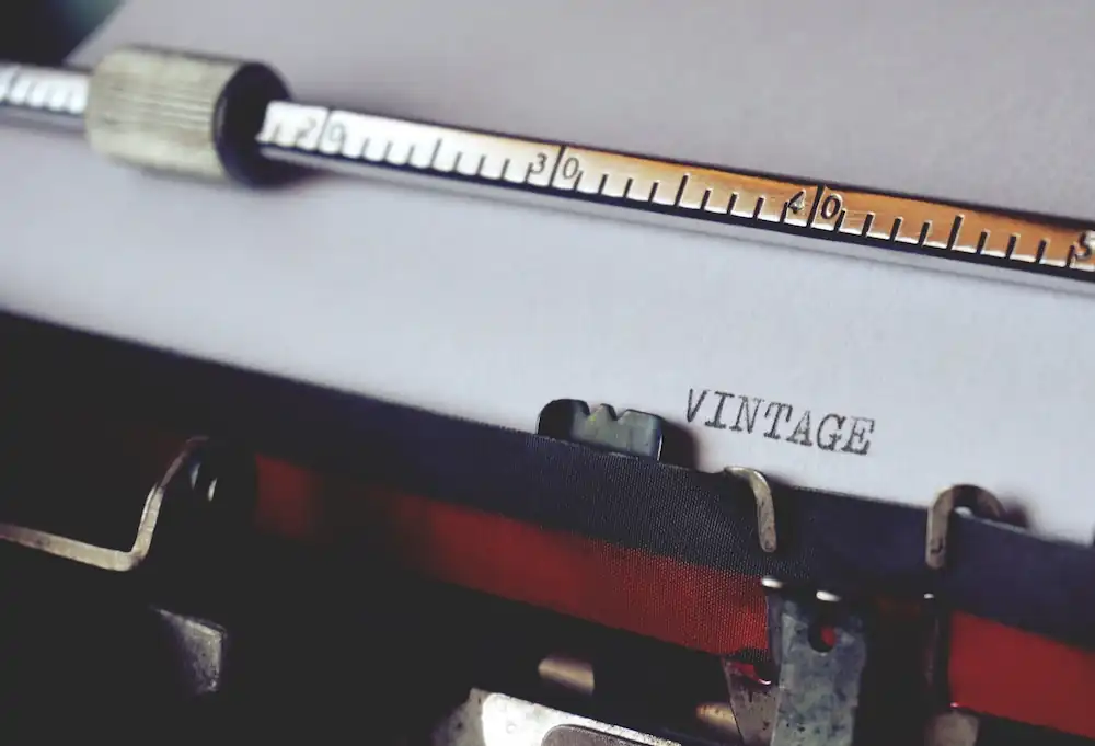 A close up photo of a typewriter and a paper with the word "vintage" written on it