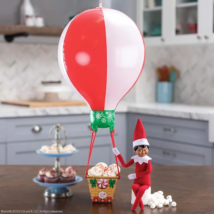 Scout elf doll sitting next to a balloon