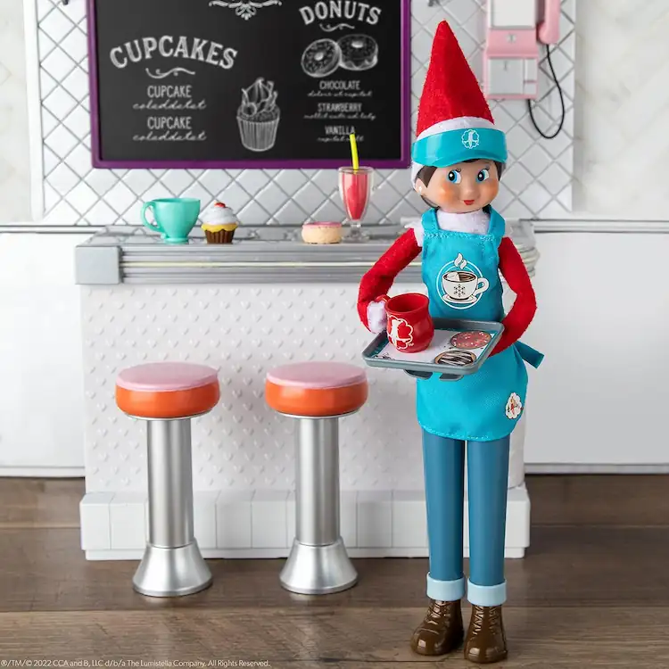 Standing scout elf doll holding a tray of goodies